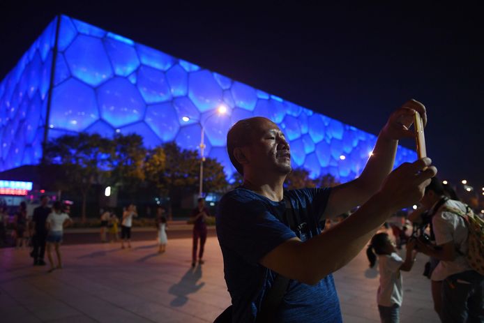 Een toerist neemt een foto voor de Watercube. In 2022 zal hier de curlingcompetitie plaatsvinden voor de Olympische winterspelen.