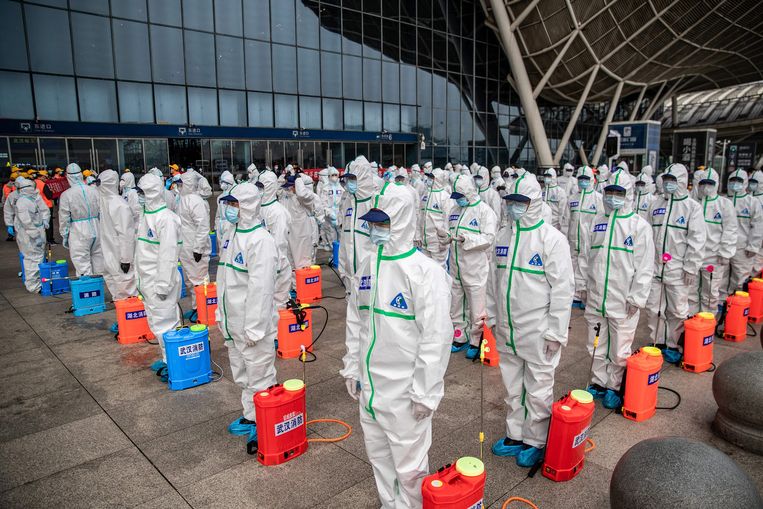 Personeel staat in het gelid, klaar om het station van de Chinese stad Wuhan te ontsmetten.
 Beeld AFP