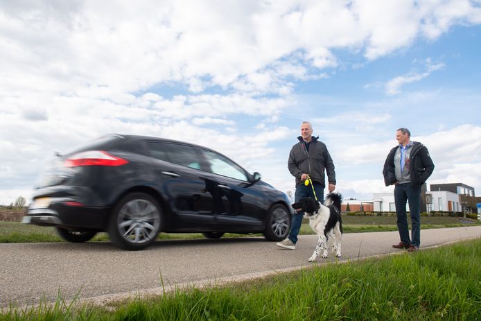 Izaak Oosthoek met hond Moos en Hans Nooren lopen langs de weg die als sluiproute wordt gebruikt en waar hard wordt gereden.