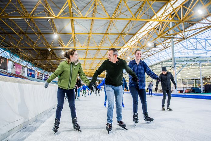 Leo van Marrewijk bindt met zijn dochters de schaatsen onder op De Uithof.