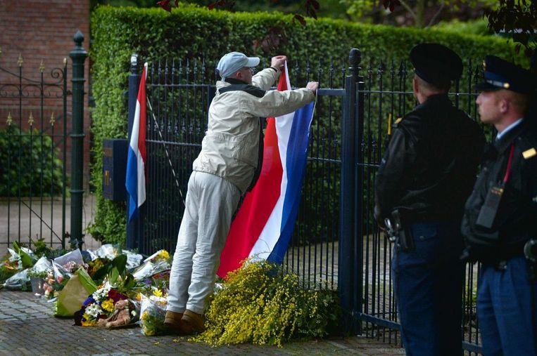 Een man hangt een vlag op aan het hek van het huis van Pim Fortuyn, daags na zijn dood in 2002. De moord gaf aanleiding tot allerlei complottheorieën. Beeld ANP