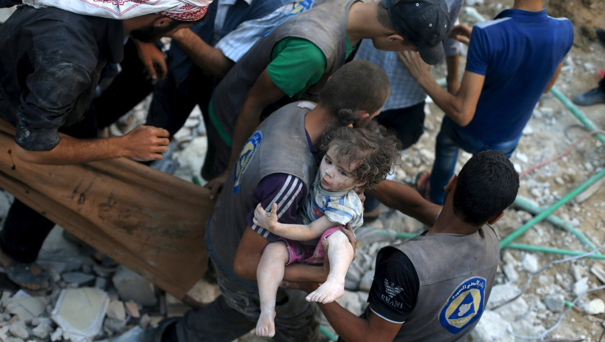 Een hulpverlener draagt een meisje weg na een bombardement op Douma bij Damascus. Rebellen schrijven de verwoesting toe aan een vatbom. Beeld reuters