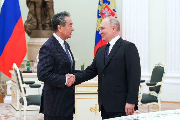 Russisch president Vladimir Poetin schudt de Chinese topdiplomaat Wang Yi de hand aan het begin van hun topontmoeting in het Kremlin eerder vandaag.