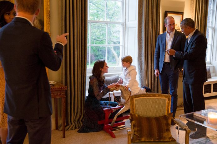 Barack Obama (rechts) en Michelle Obama (links) op bezoek in Kensington Palace in 2016. Prins George speelt op een hobbelpaard in het midden.