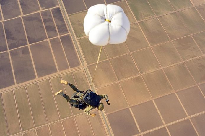 Een Belgische paracommando maakt een parachutesprong boven het woestijnachtige Yuma.