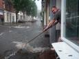 In Arnhem probeert een man het water uit zijn huis te verwijderen na een hoosbui.