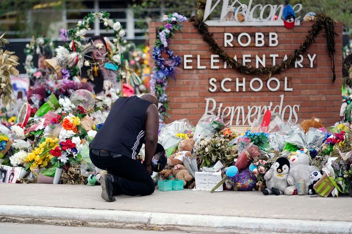 Een man knielt bij een herdenkingsplek bij de Robb Elementary School in Uvalde (Texas), waar in mei negentien leerlingen en twee leraren om het leven kwamen bij een schietpartij.