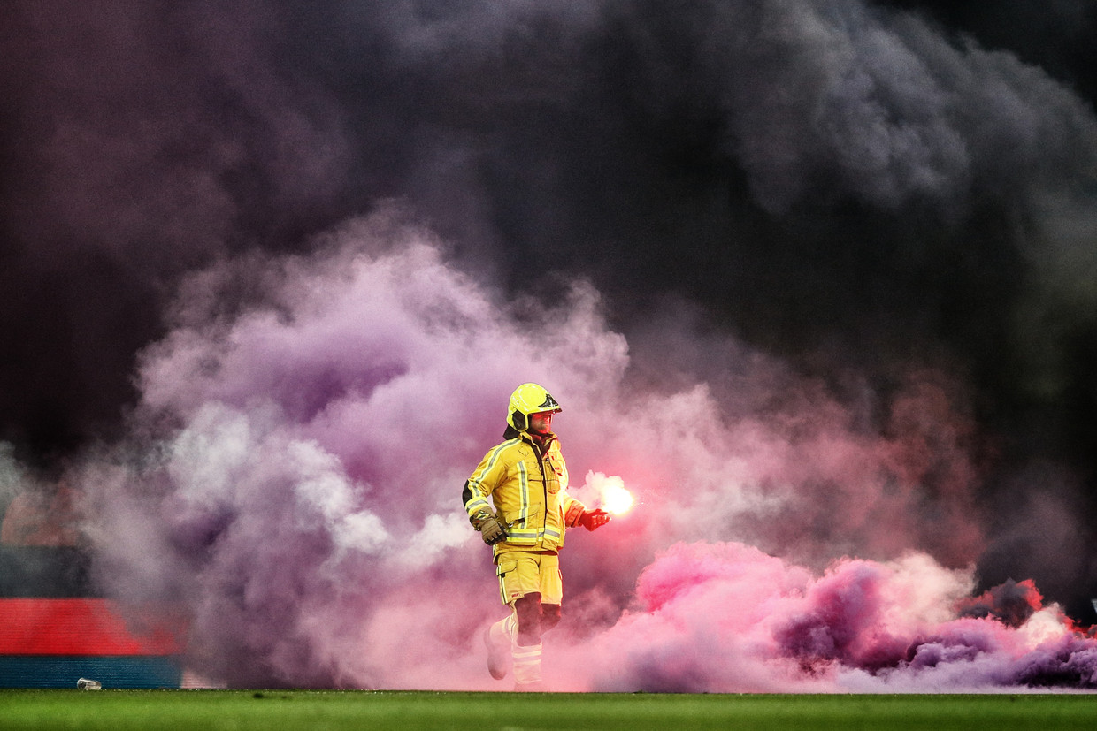 De brandweer haalt vuurwerkpijlen weg van het veld tijdens de match vrijdag.
