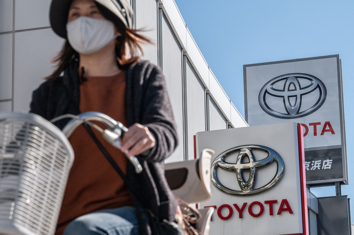 Een vrouw passeert een Toyota-dealer in Tokio. Het automerk versloeg in 2022 opnieuw concurrent VW als grootste autobouwer. Beeld AFP