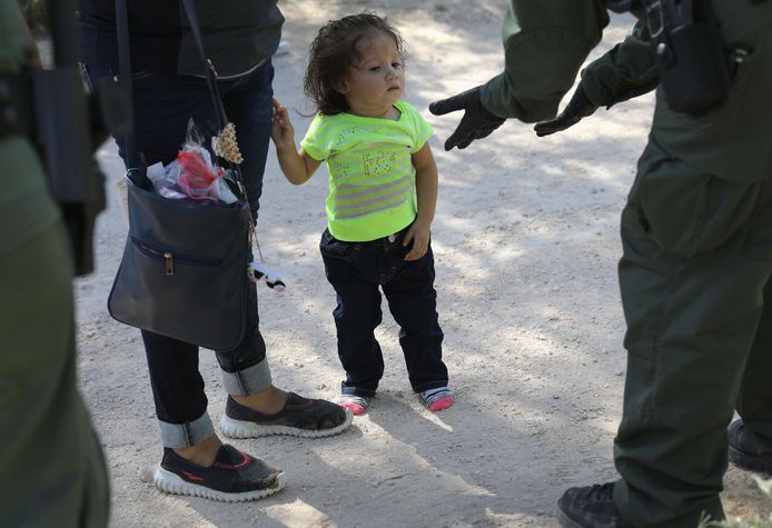 Een agent neemt een familie in hechtenis aan de Mexicaans-Amerikaanse grens.