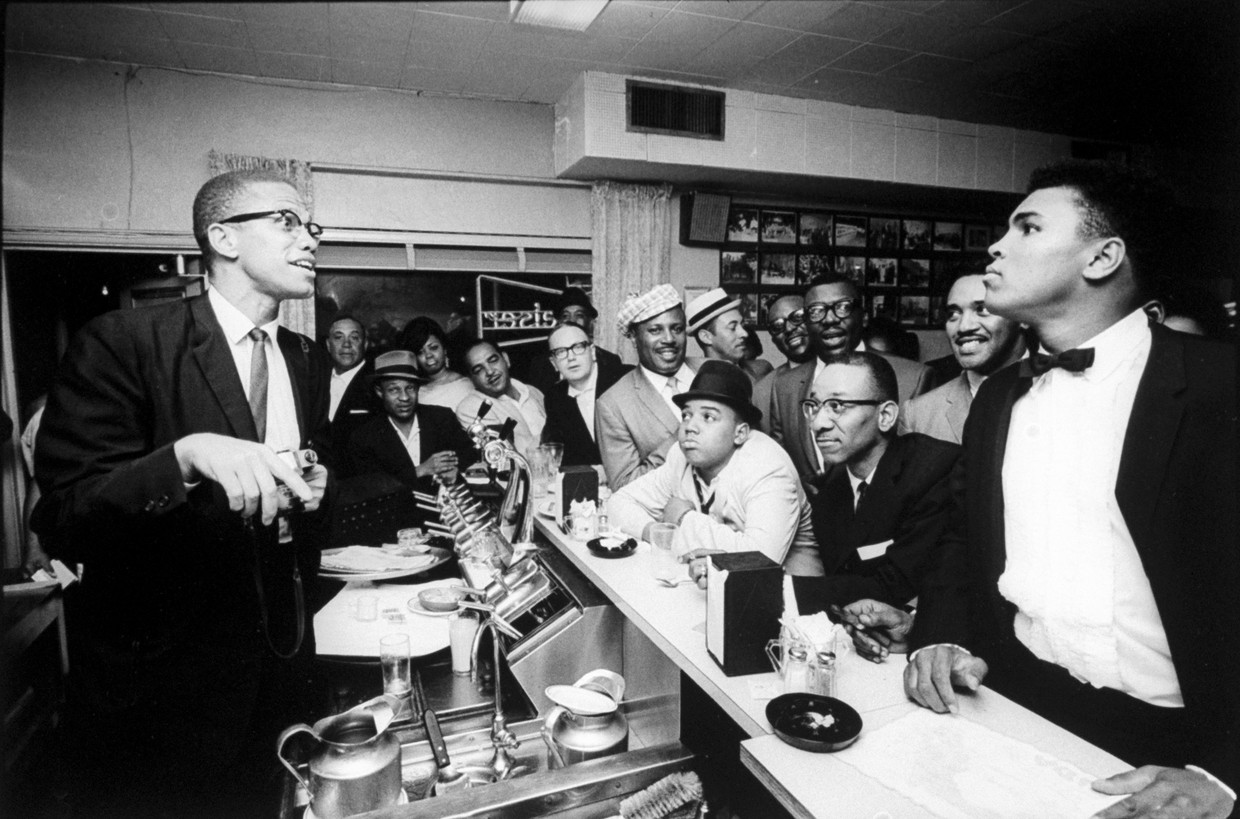 Miami 1963. Malcolm X (l.) dolt wat met Muhammad Ali, die gespeeld verontwaardigd is, terwijl fans zijn WK-titel vieren. Beeld Getty Images