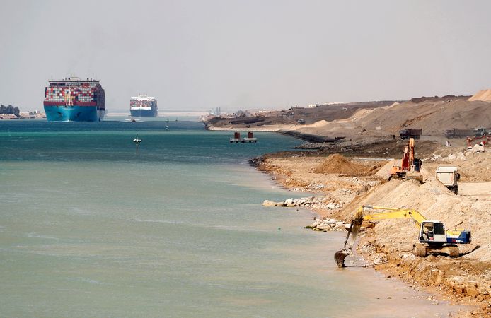 Containerschepen varen door het Suez-kanaal dat wordt verbreed door de graafmachines rechtsvoor. Archiefbeeld.