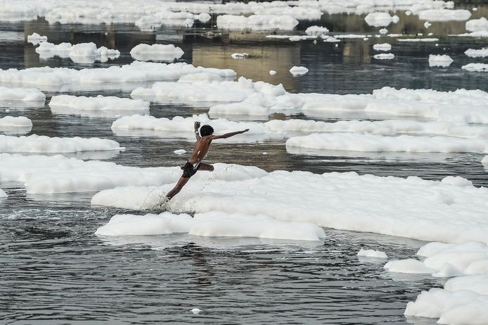 Het lijken net ijsschotsen..... die schuimkoppen waar de Indiase jongen over lijkt te springen.  De Yamuna rivier in New Delhi behoort tot een van de meest vervuilde rivieren in India. Foto Chandan Khanna