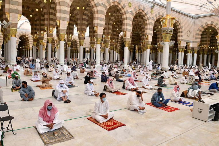 Mannen bidden met mondmaskers op in de moskee van Medina. Beeld VIA REUTERS