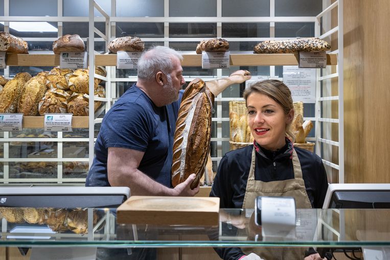 Terwijl eigenaar Emmanuel de verse broden in het rek legt, bedient een medewerker de klanten. Beeld Elisa Maenhout