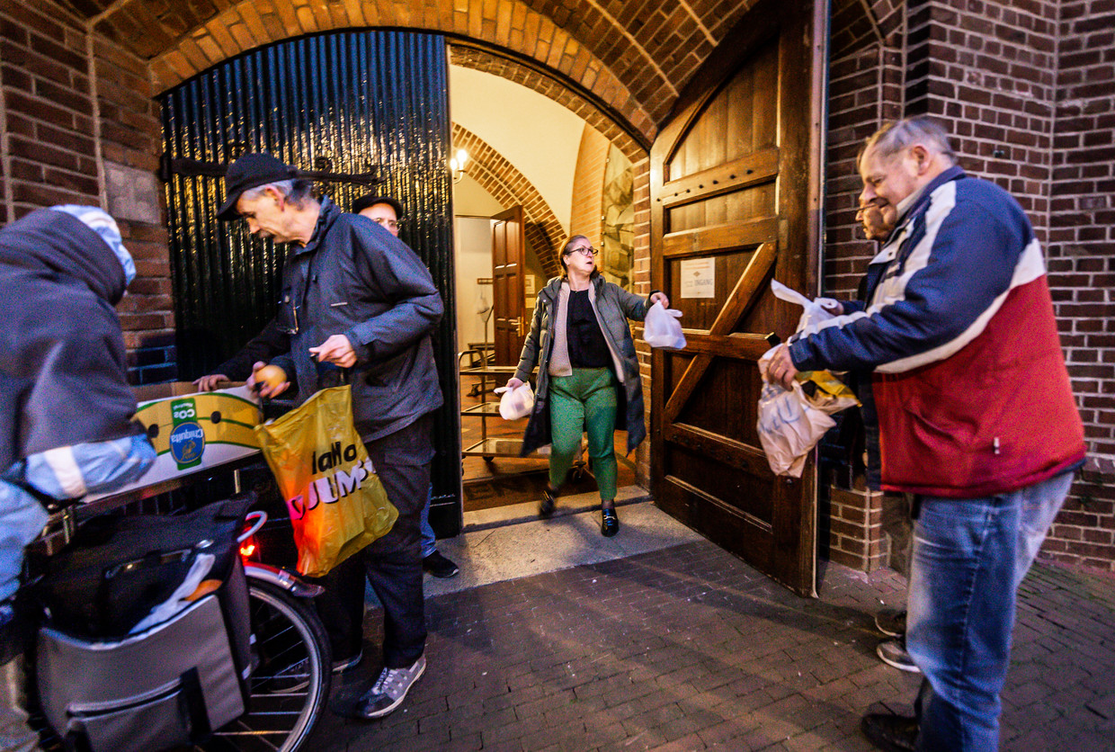 Nederland, Helmond, 25/01/2023
Bij de hoofdingang van de Jozefkerk in Helmond delen vrijwilligers gratis maaltijden uit.