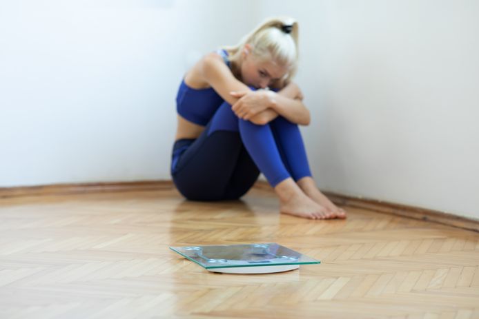 Sad teenager girl with scales on floor