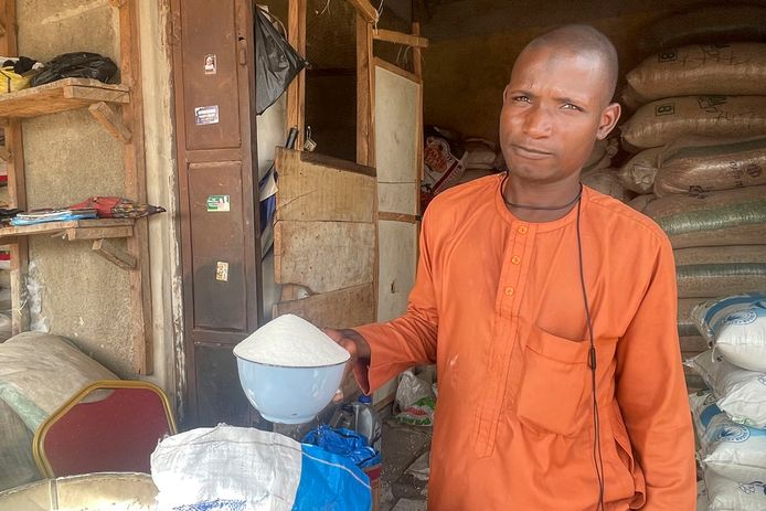 Isa Ahmed laat de kristalsuiker zien die hij verkoopt in zijn winkel op een markt in Abuja, Nigeria.