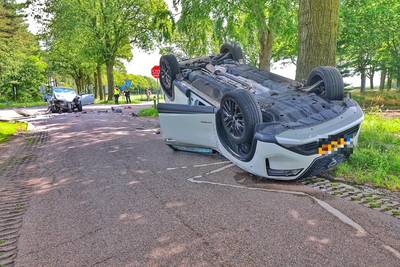 Auto belandt ondersteboven tegen boom bij botsing met andere auto: inzittende gewond en veel schade