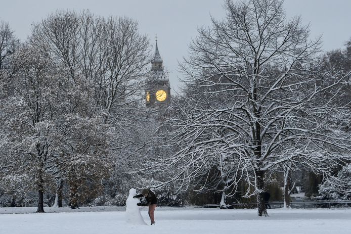 A Londoner makes a snowman in a park with Big Ben in the background.
