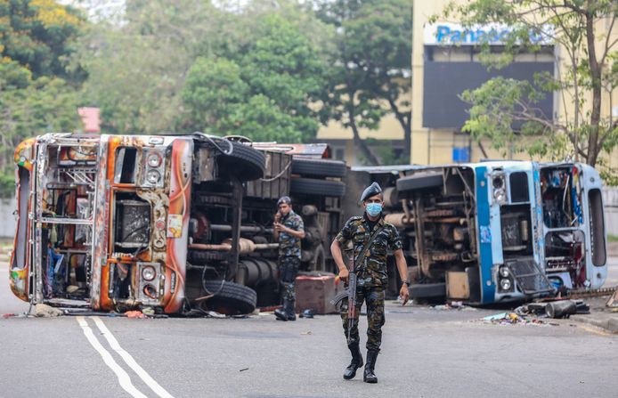 Gewapende militairen bij twee buswrakken na het gewelddadig protest in hoofdstad Colombo op maandag.