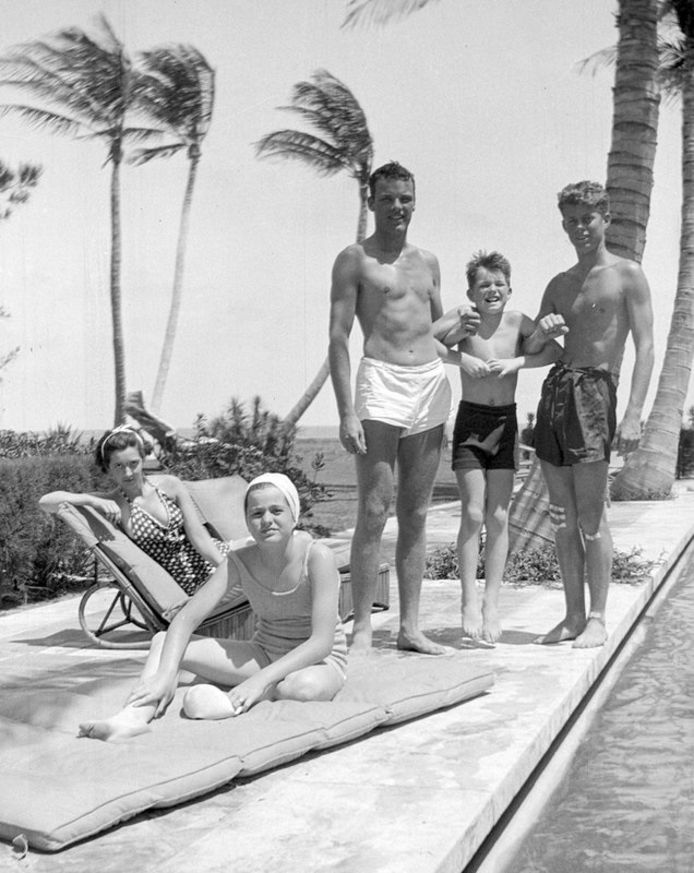 John F. Kennedy (rechts), Robert F. Kennedy (tweede van rechts) en Patricia Kennedy (vooraan links), samen met enkele vrienden aan het zwembad in Palm Beach, Florida.