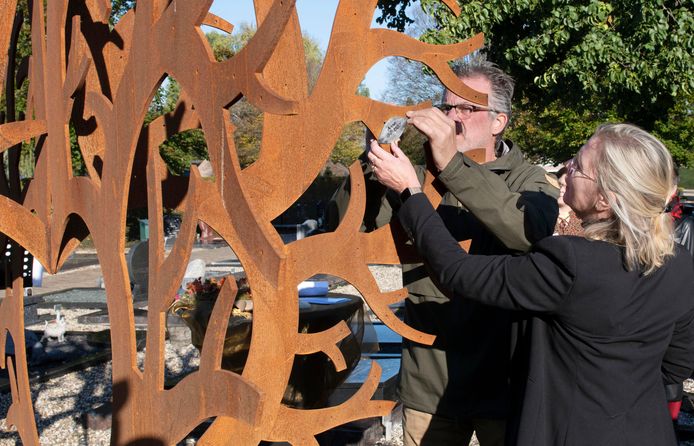 Margreet en Herman Willemsen hangen het plaatje met de naam van hun dochter Anne in de Gedenkboom op de begraafplaats in Dodewaard.