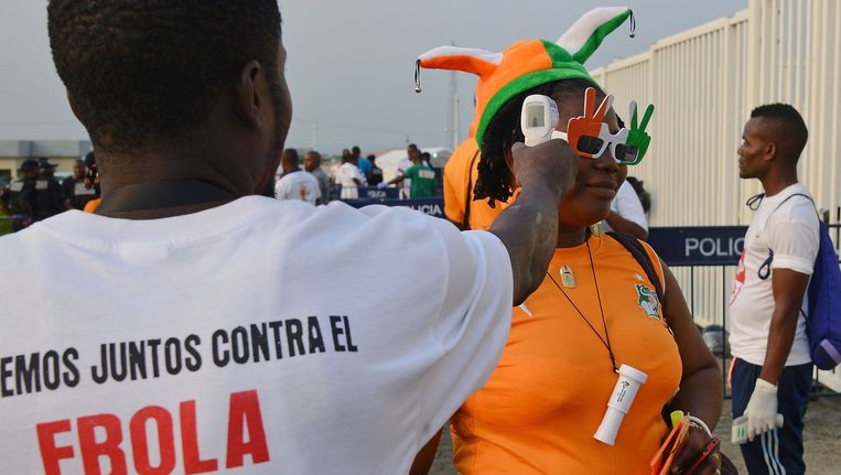 Een gezondheidswerker meet de lichaamstemperatuur bij bezoekers van de voetbalwedstrijd tussen Kameroen en Ivoorkust voor de Africa Cup in Malabo. Beeld afp