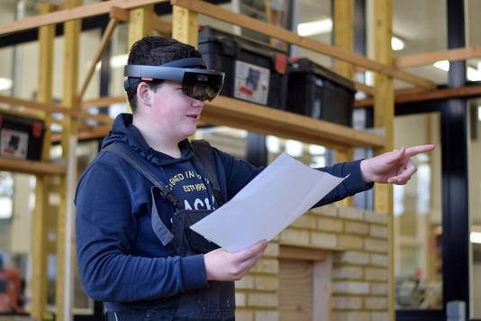 Een van de derdejaars leerlingen van VMBO basis kader kan door de hololens zijn ontwerp van de bouwplaats in het werkelijke formaat in de ruimte geprojecteerd zien.