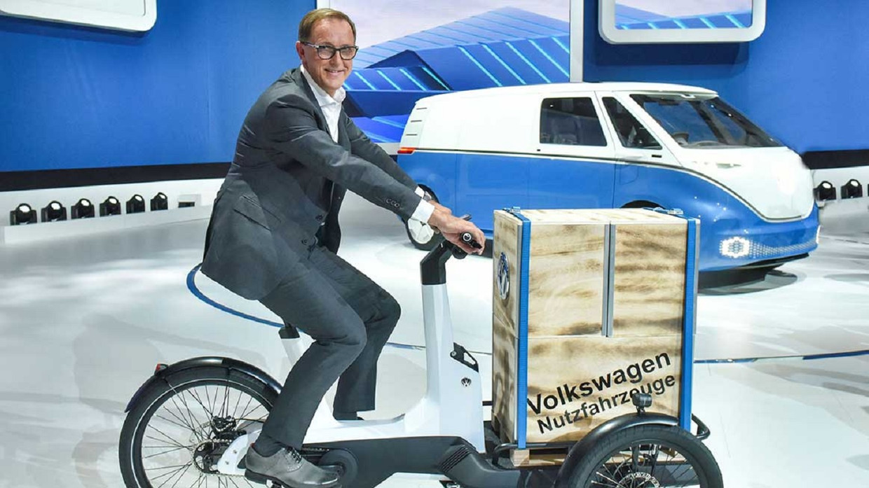De elektrische transportfiets van Volkswagen, met op de achtergrond een concept van het elektrische busje dat VW gaat maken. Beeld VW