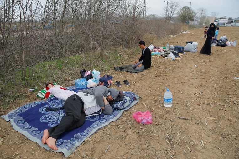 Migranten rusten uit in de buurt van de landsgrens tussen Turkije en Noord-Griekenland. Beeld REUTERS