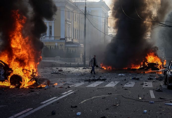 Man loopt tussen brandende auto's in Kiev.