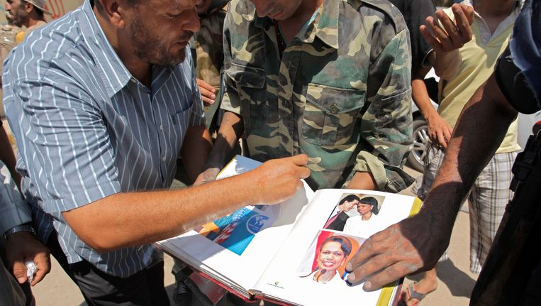 Opstandelingen bladeren door het in de kamers van Kaddafi gevonden fotoboek van Rice Beeld AP