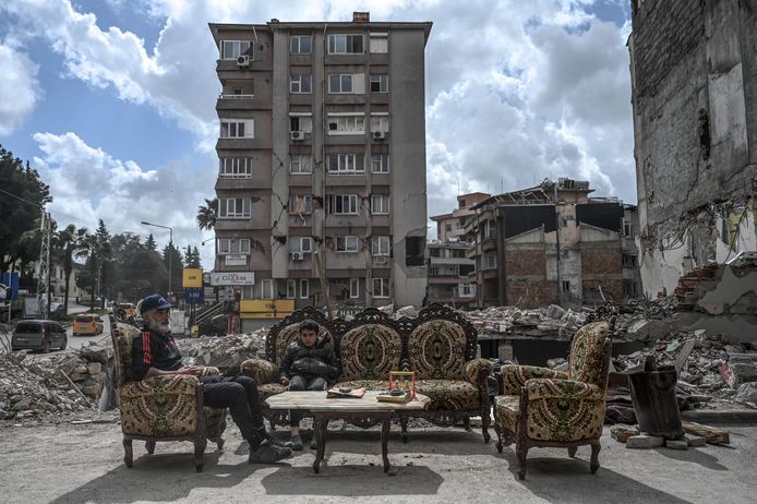 Een vader en zijn zoon buiten tussen de puin van vernielde gebouwen in het Turkse Antakya. Beeld van 5 april.