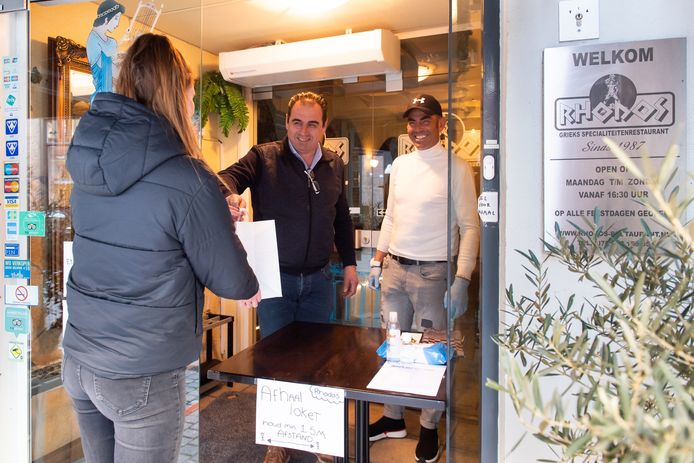 Yannis Papadopoulos van Restaurant Rhodos in Breda overhandigt een afhaalmaaltijd  aan een klant.
