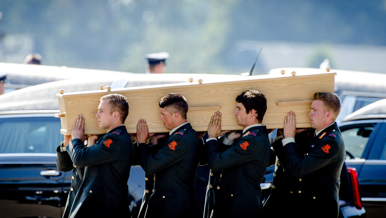 Militairen dragen op de dag van nationale rouw kisten met de slachtoffers van MH17 naar de lijkwagens. Beeld anp