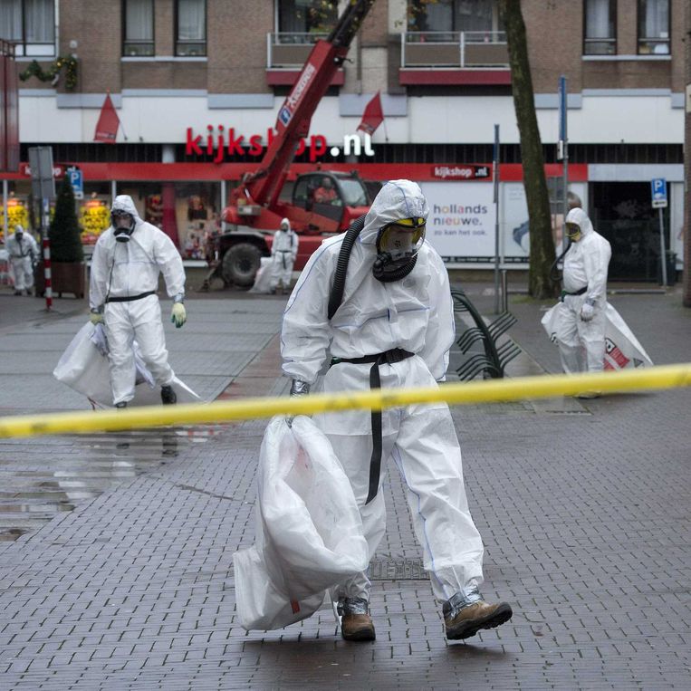 Mannen in witte pakken ruimen asbest op in de binnenstad. Beeld anp
