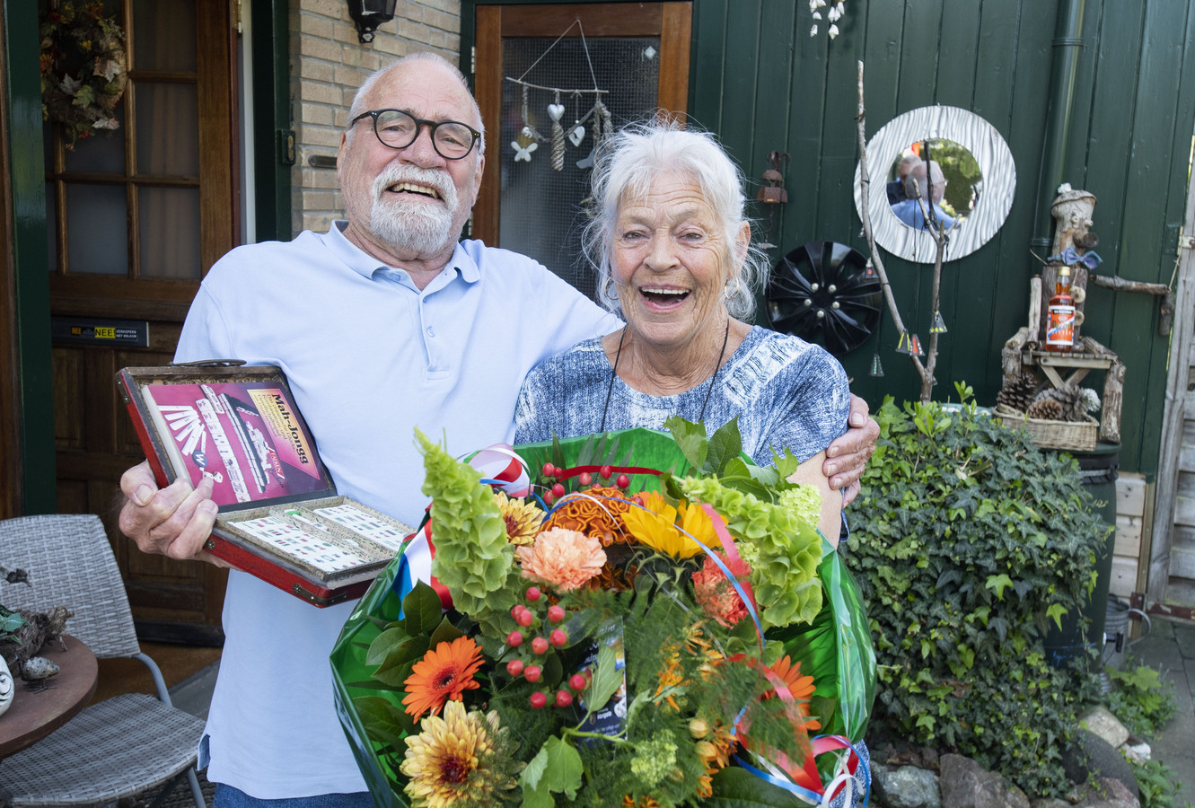 Echtpaar Jan en Ada Ketzer krijgt lintje: niet de decoratie zelf, maar bos bloemen en taart van de gemeente. Zij hebben het spel Mahong gepromoot in Nederland .