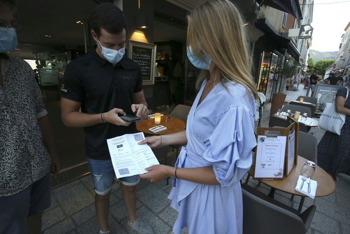Een restauranthouder checkt de vaccinatiebewijzen van twee toeristen op Corsica.