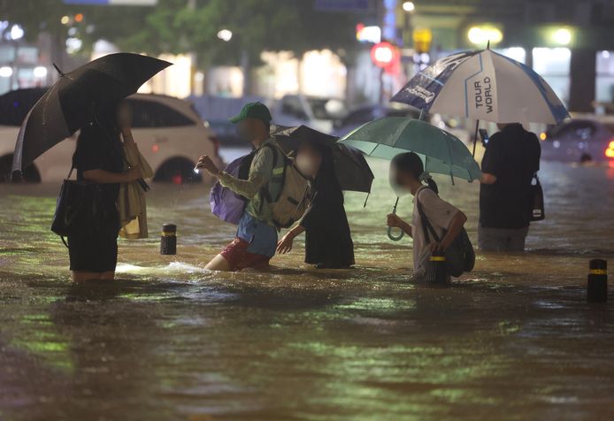 Mensen waden door een overstroomde weg in Seoul, Zuid-Korea.