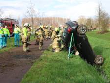 Auto op de kop in sloot in Sint-Oedenrode, brandweer haalt bestuurder eruit