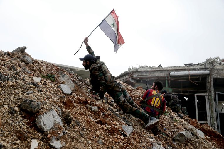 In this Dec. 5, 2016 file photo, a Syrian army soldier places a Syrian national flag during a battle with rebel fighters at the Ramouseh front line, east of Aleppo, Syria.  Beeld AP