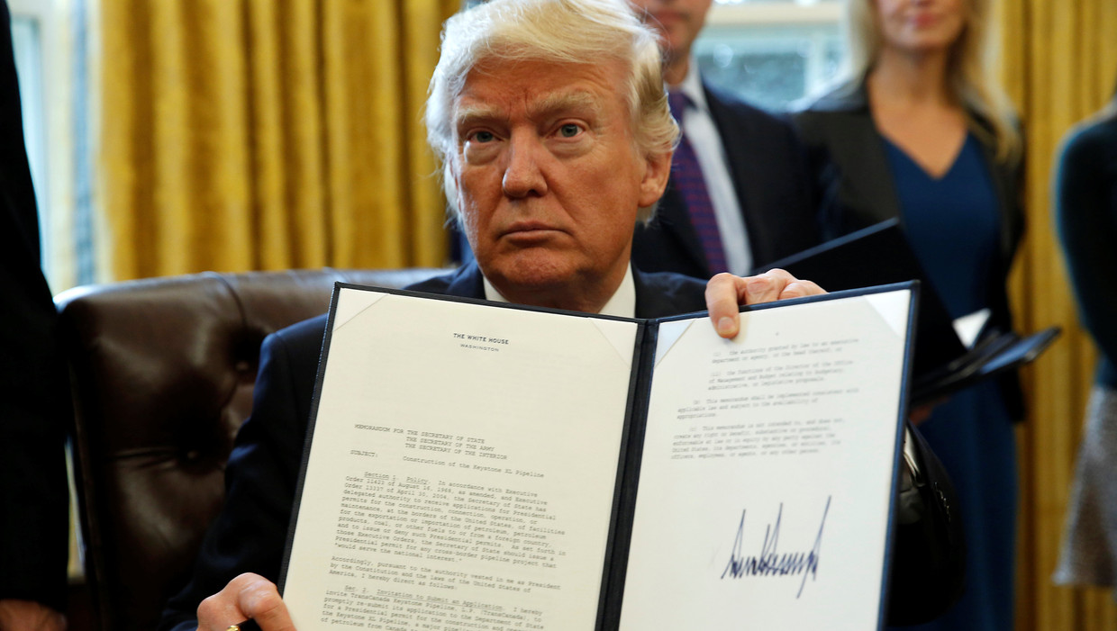Trump houdt het decreet omhoog dat hij dinsdag heeft ondertekend, aangaande de aanleg van twee omstreden oliepijpleidingen. Beeld REUTERS