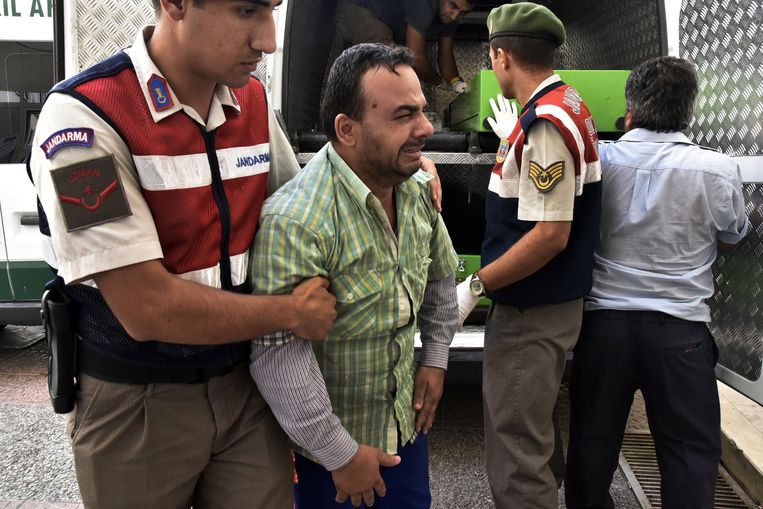 Een Turkse agent probeert de Syriër Hayat Sabir Burhan te troosten. Hij overleefde de boottocht, zijn vrouw (32) en zoontje (3) niet. Beeld ap