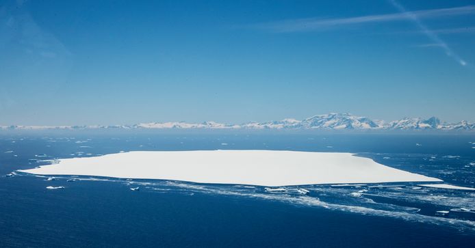 Vooraan in beeld ijsberg A-68D, die afbrak van het noordelijke deel van 'moederberg' A68A. In de achtergrond het eiland South Georgia.