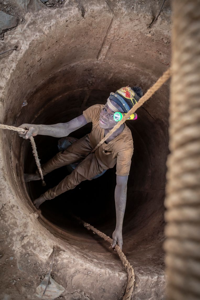 Een jongen laat zich afzakken in een van de vele mijnschachten van de goudmijn bij Mougoumi. Beeld 