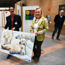 Elma Greven poseert trots met het door haar gekochte schilderij met drie ijsberen, naast haar voorzitter Leo Vlemmix.