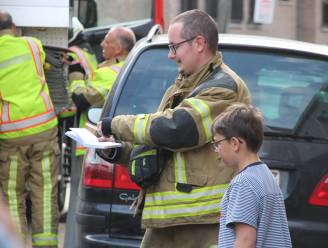 Jongen vraagt handtekeningen van brandweerlui na brand in de straat