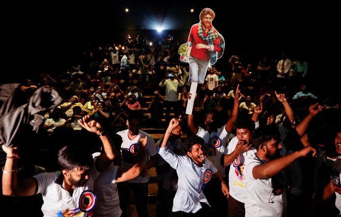 Fans of Tamil movie star Rajinikanth dance in a cinema hall during his movie.