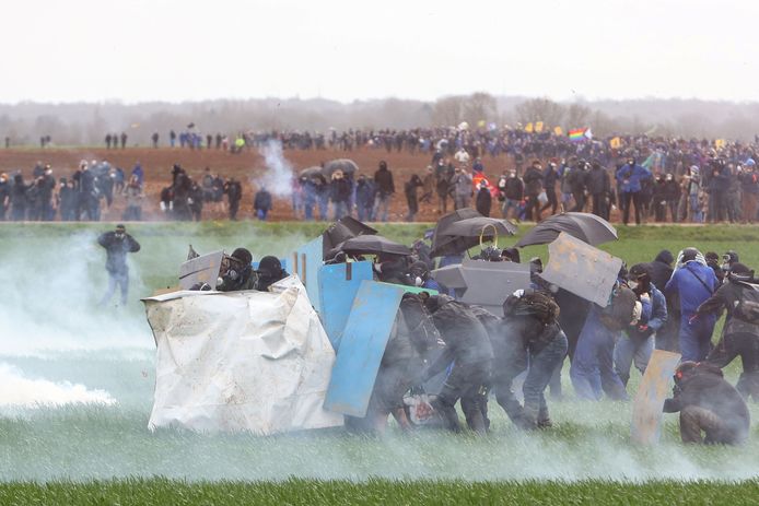 Demonstranten nabij het Franse dorp Sainte-Soline proberen zich te beschermen tegen het traangas van de oproerpolitie.